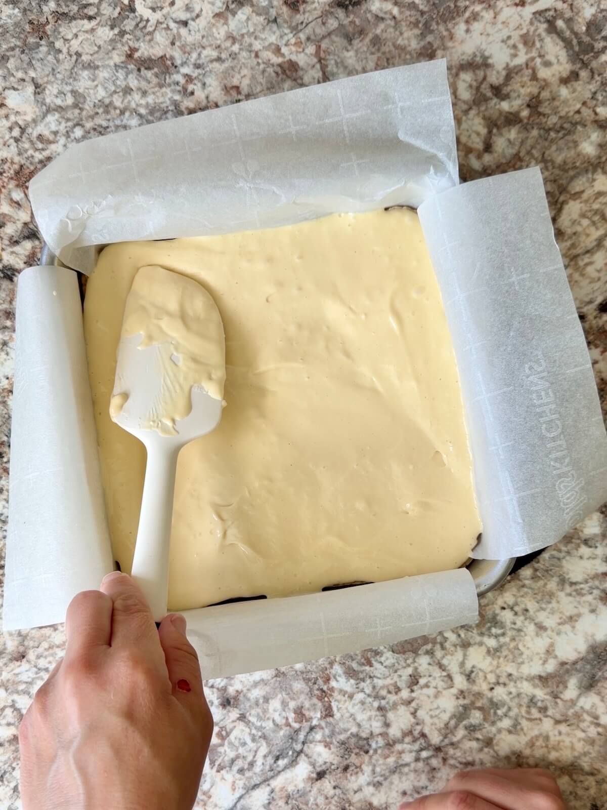 The cheesecake layer being spread on top of the sourdough crust.