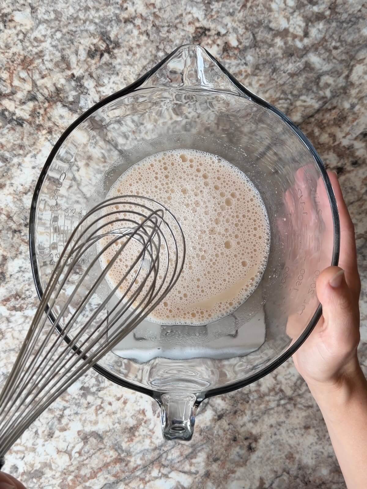 Water and sourdough starter whisked together in a bowl.