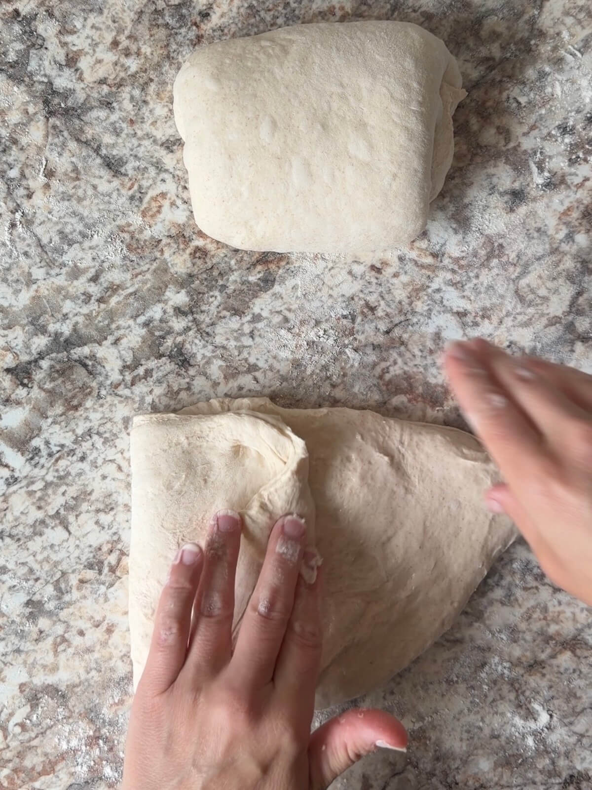 Sourdough bread dough being shaped on a floured counter.