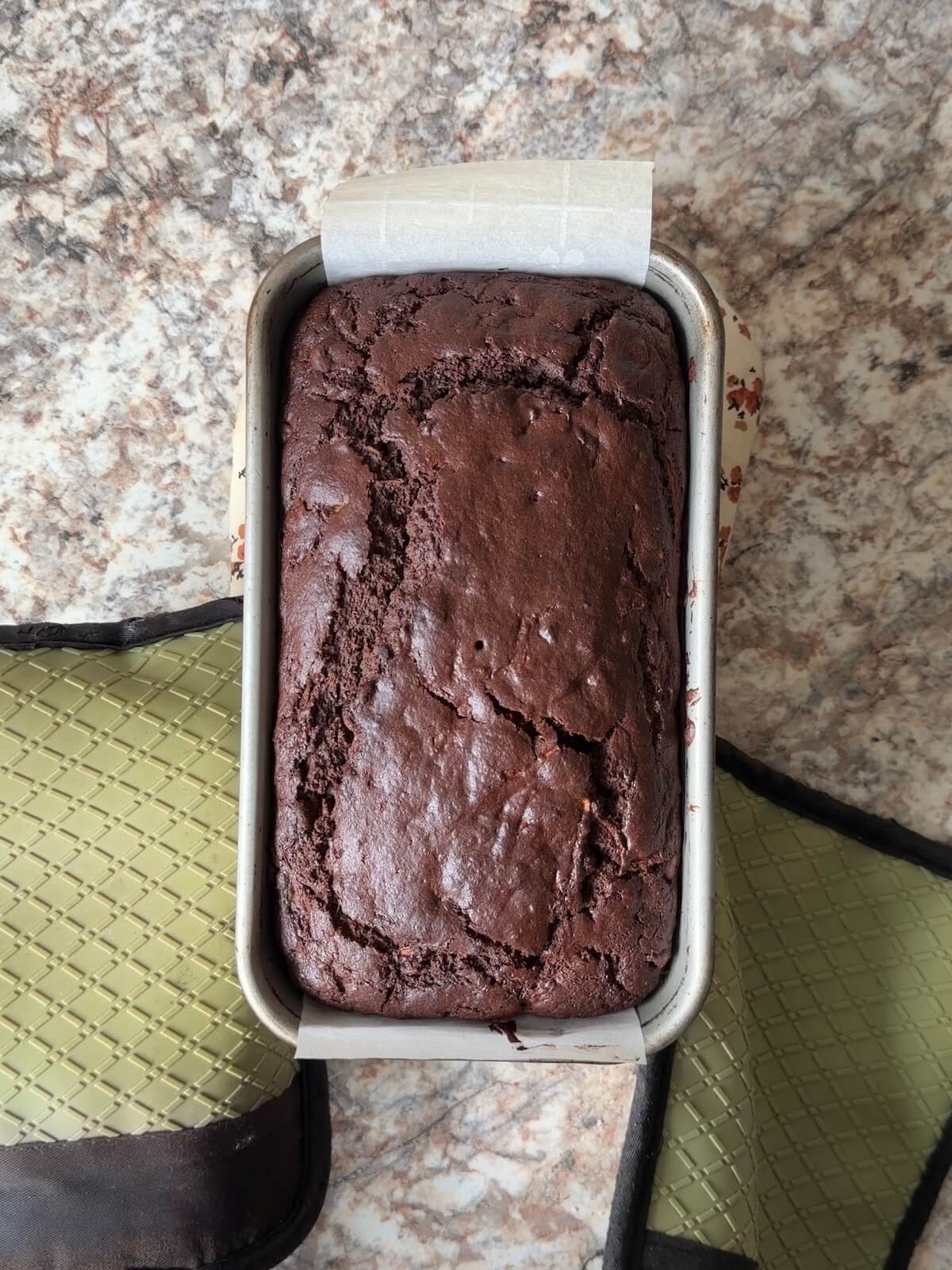 A baked loaf of sourdough chocolate zucchini bread in a loaf pan.
