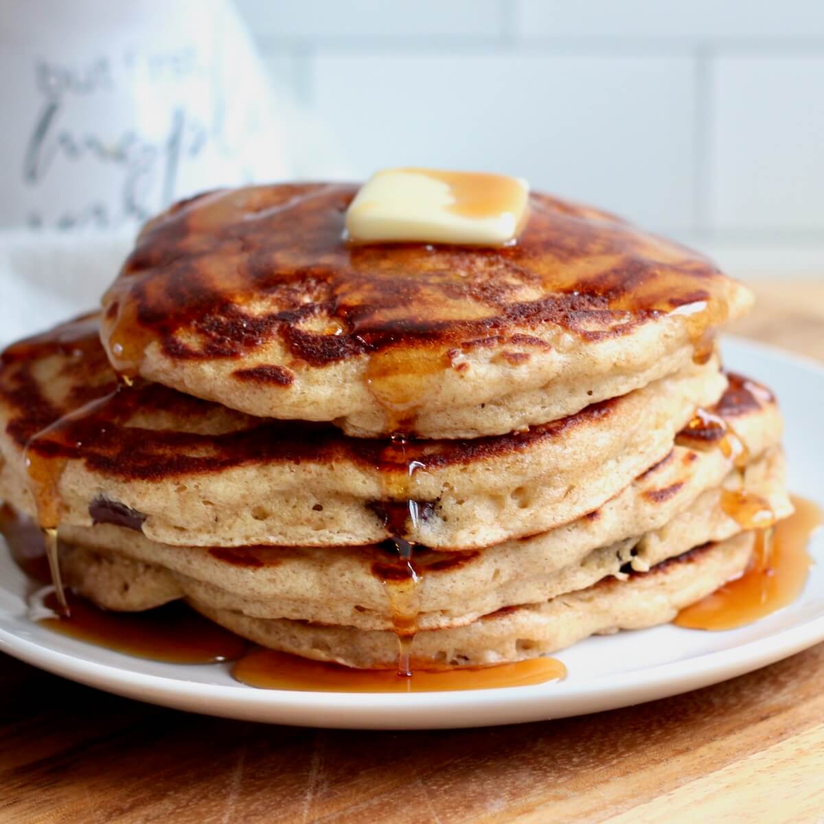 A stack of sourdough discard pancakes with butter and maple syrup on a small plate.