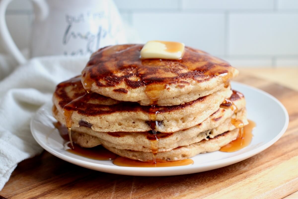 A stack of sourdough discard pancakes with butter and maple syrup on a small plate.