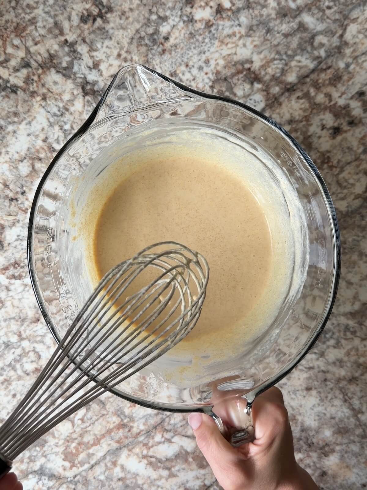 Sourdough discard, buttermilk, and other wet ingredients whisked together in a bowl.