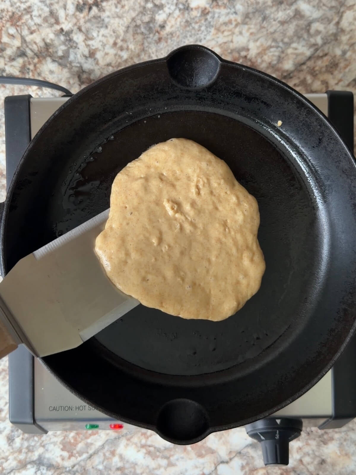 A sourdough discard pancake being cooked in a cast iron skillet.