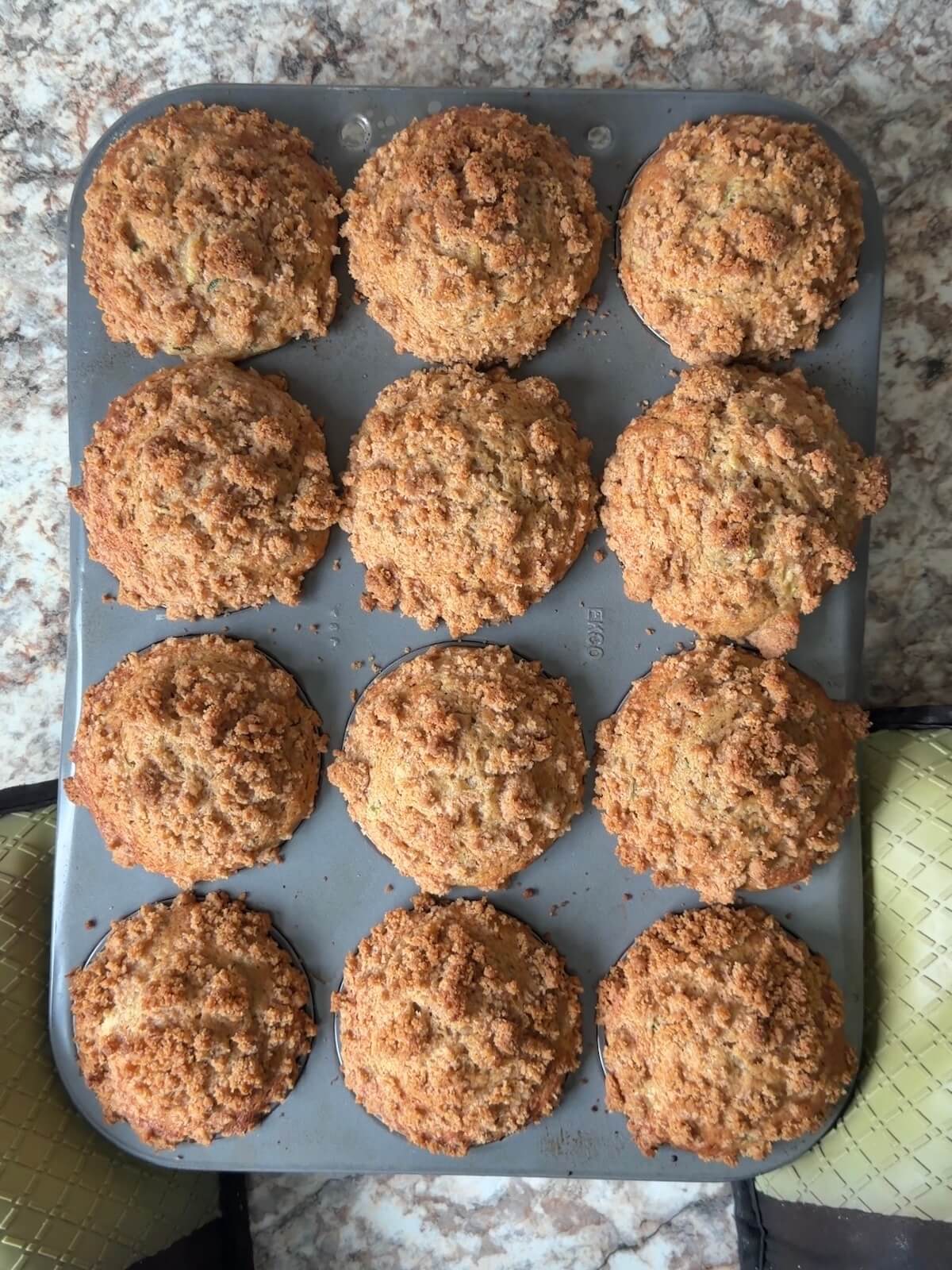 Baked cinnamon streusel sourdough zucchini muffins in a muffin pan.