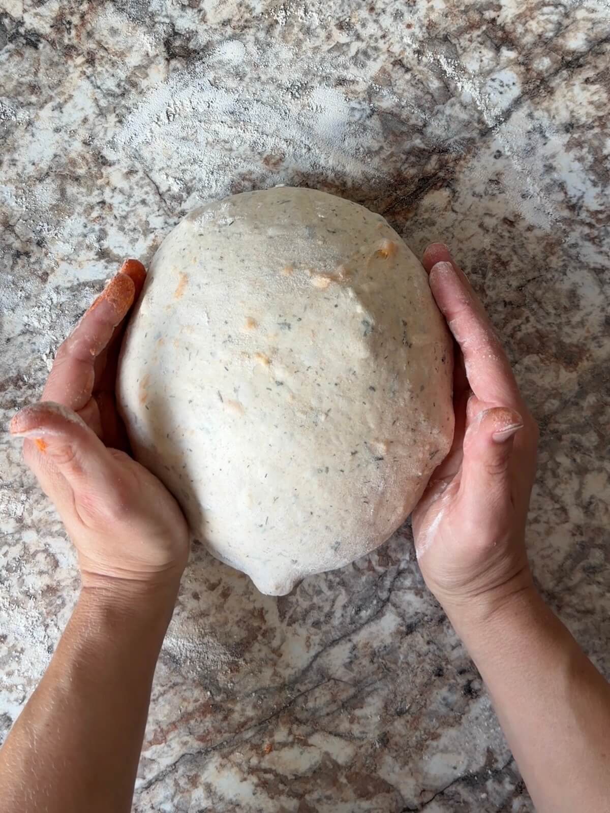 Two hands shaping the dough into a ball.
