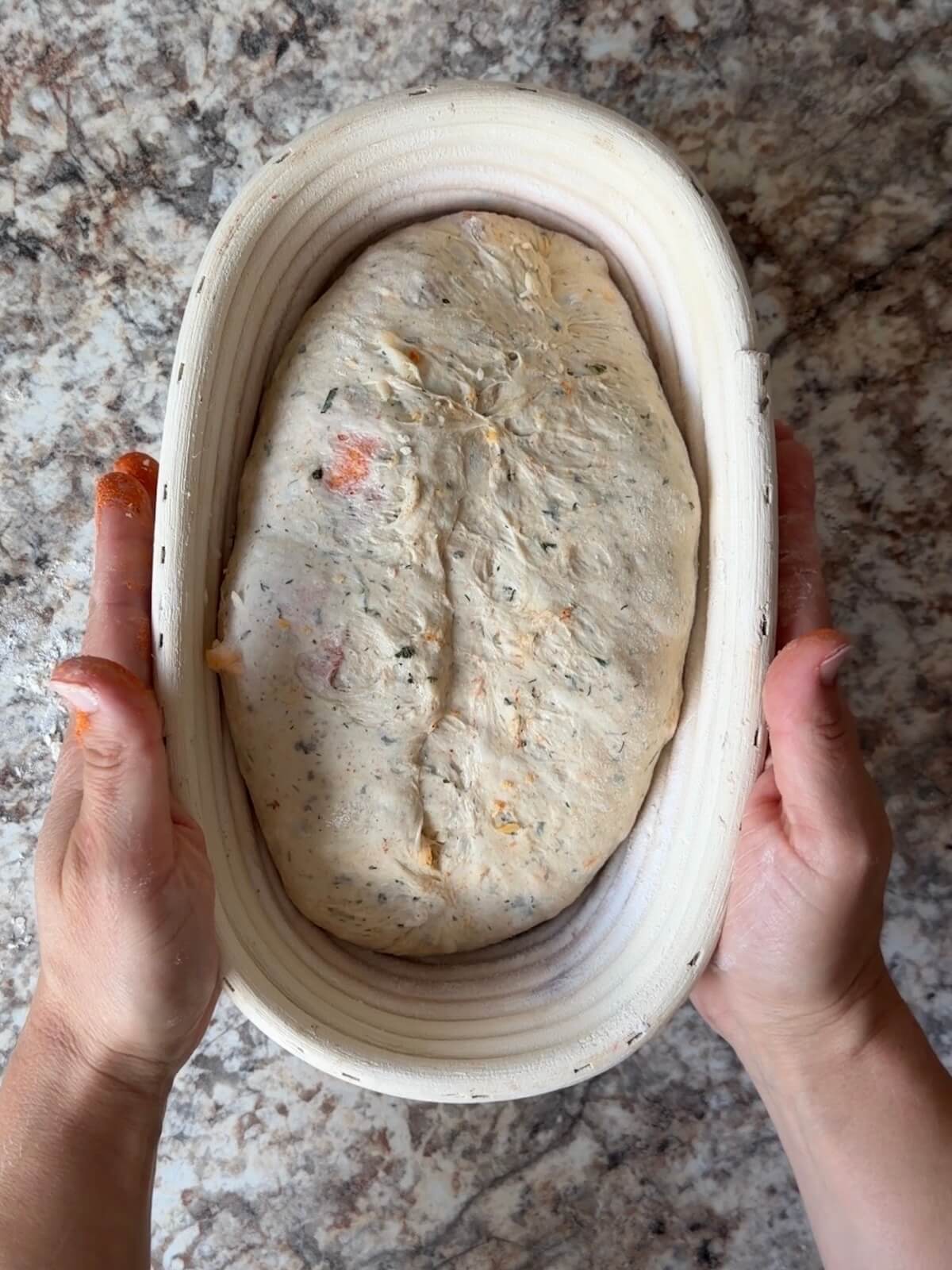 Buffalo chicken sourdough bread dough in an oval proofing basket before cold proofing overnight.