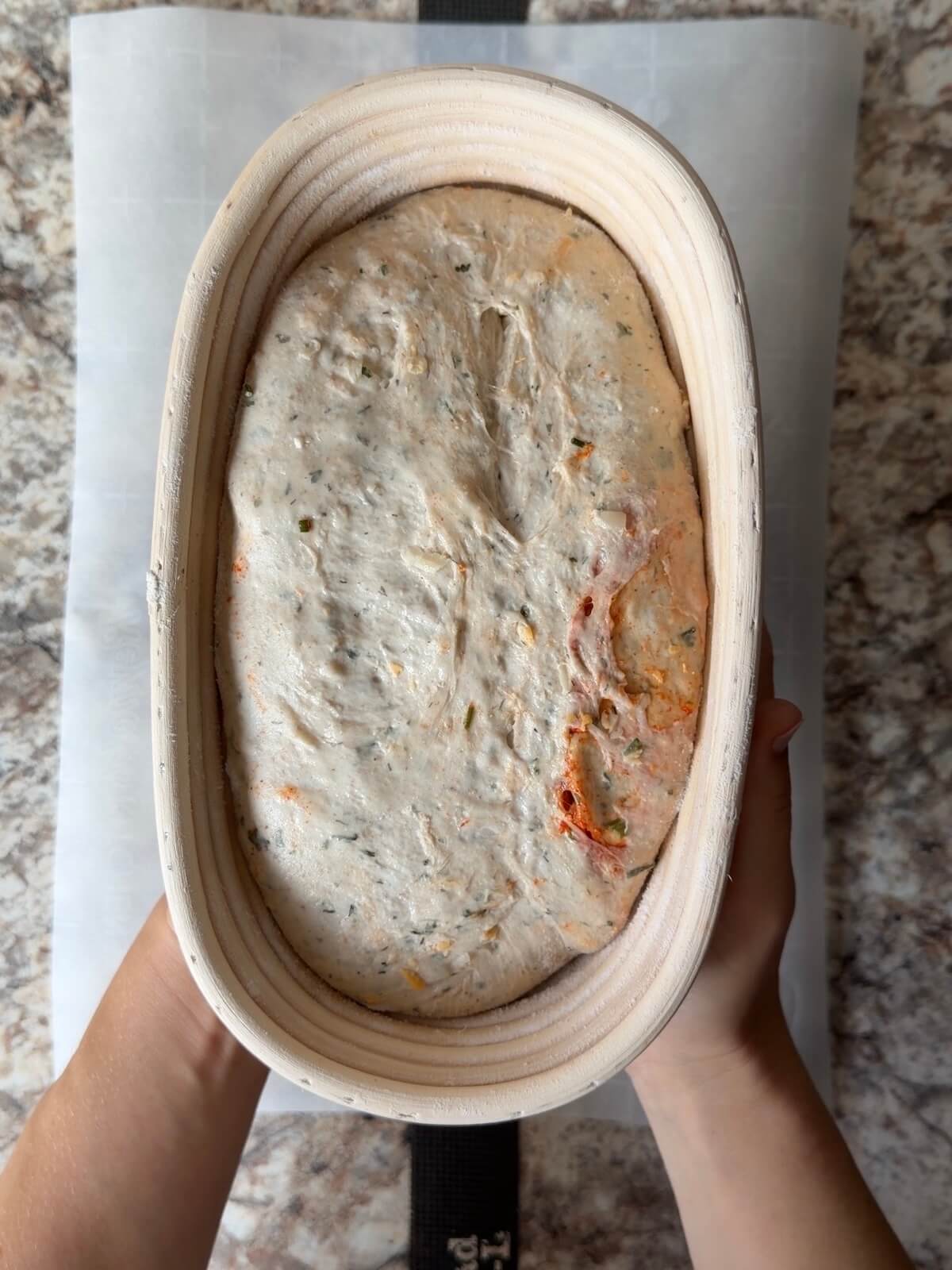 Buffalo chicken sourdough bread dough in an oval proofing basket after cold proofing overnight.