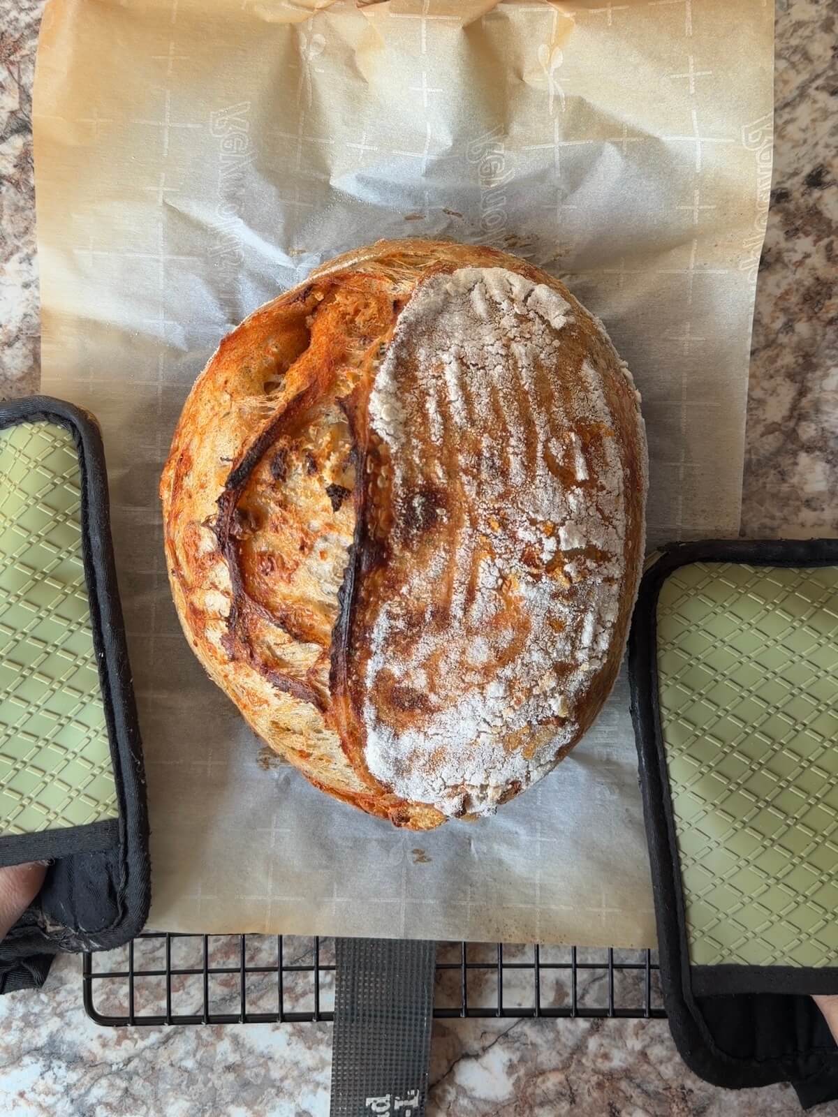 A baked loaf of buffalo chicken dip sourdough bread on a wire cooling rack.
