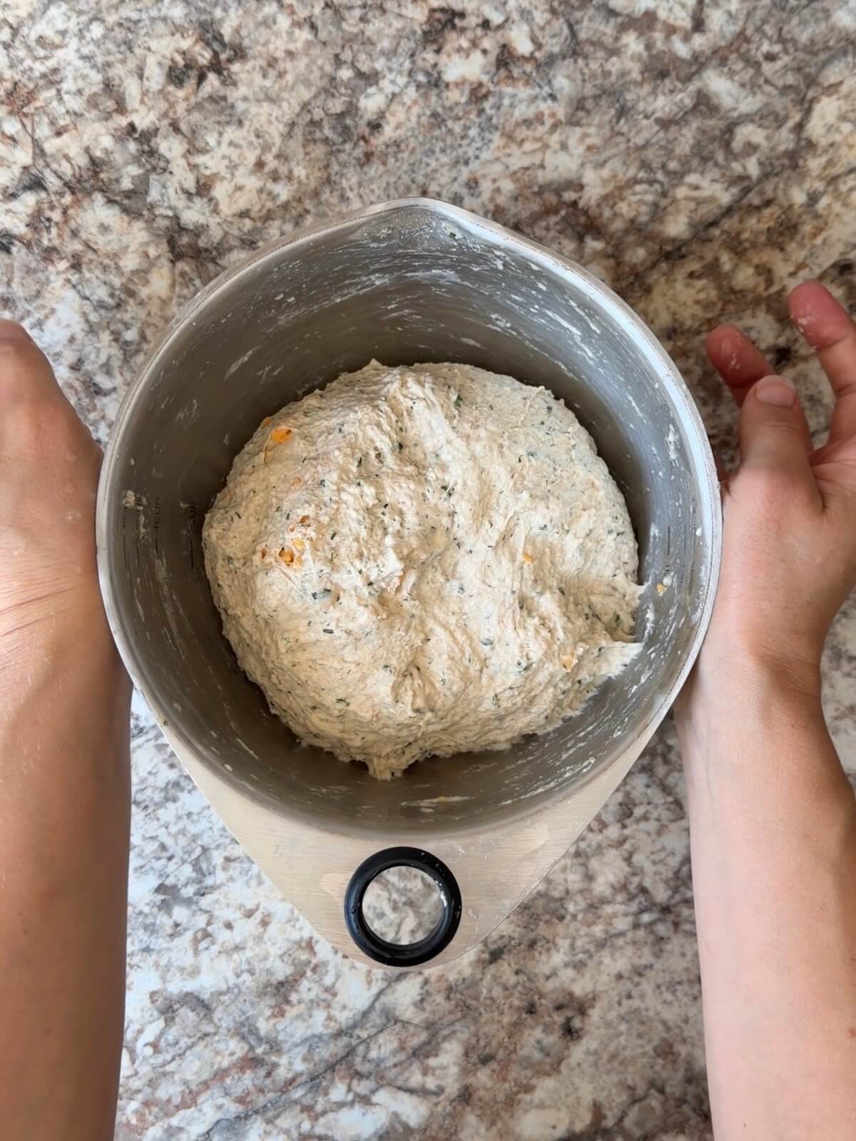 Buffalo chicken dip bread dough with cheddar cheese folded into it in a mixing bowl.