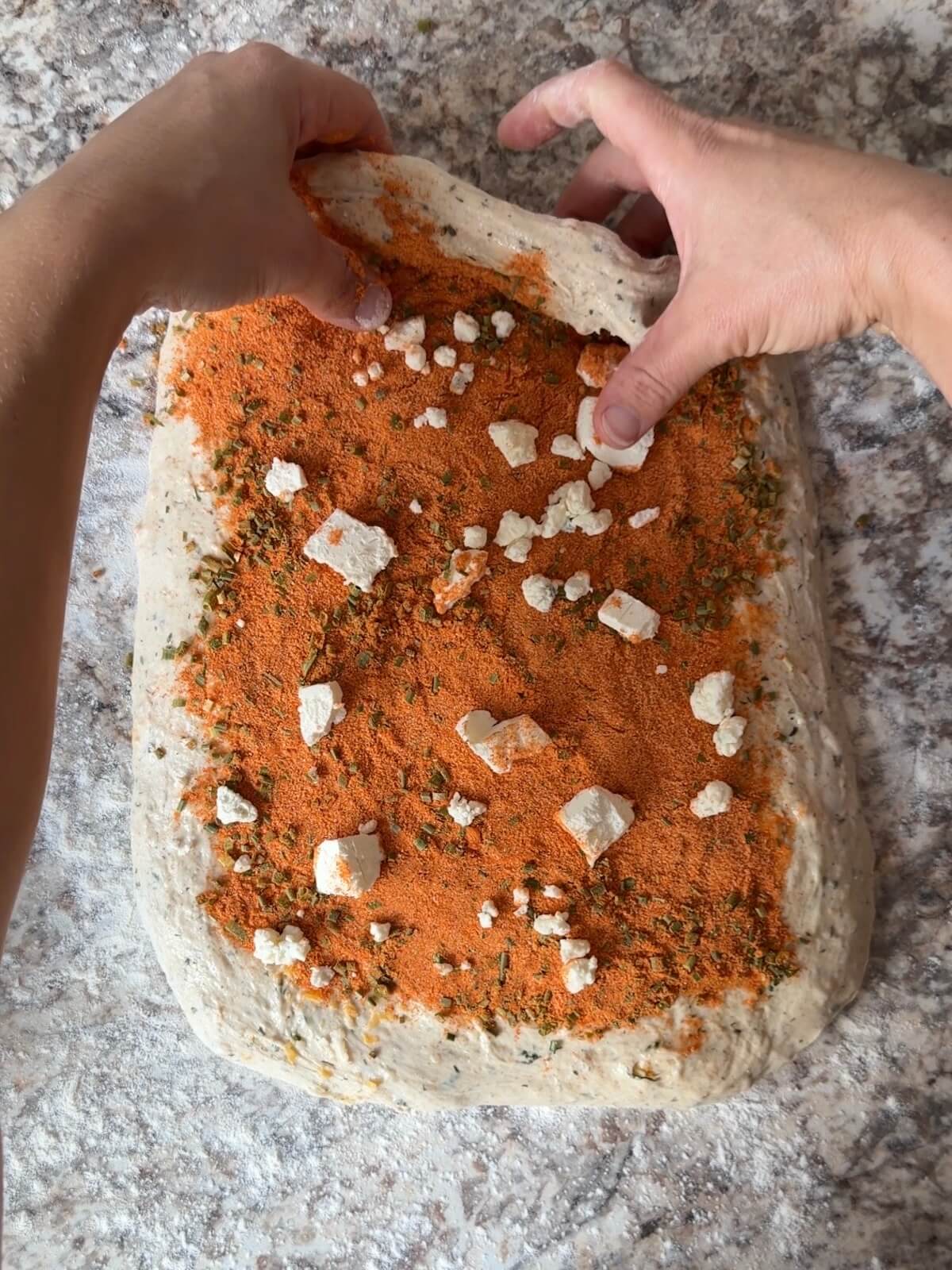 Buffalo chicken sourdough bread dough with Frank's RedHot Seasoning and blue cheese being folded in during shaping.