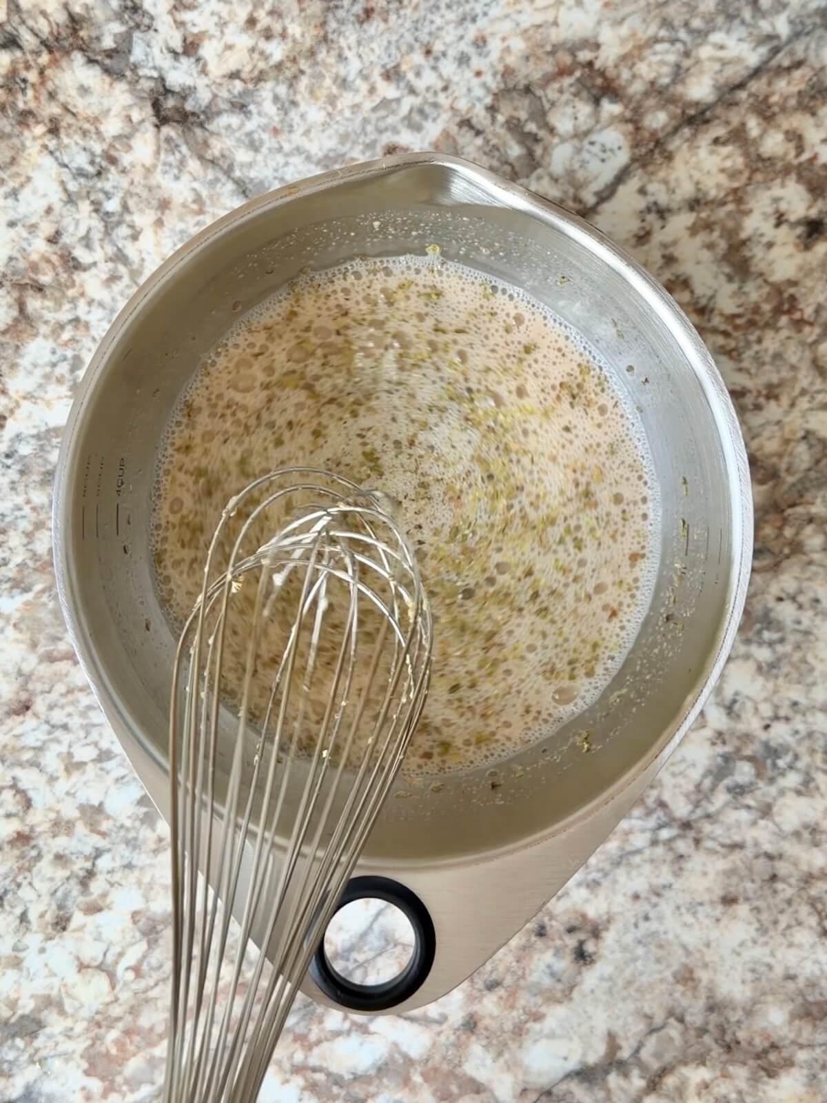 Sourdough starter, water, and pizza seasoning whisked together in a bowl.
