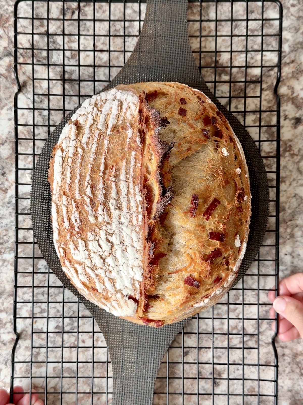 A baked loaf of pepperoni pizza sourdough bread on a wire cooling rack.