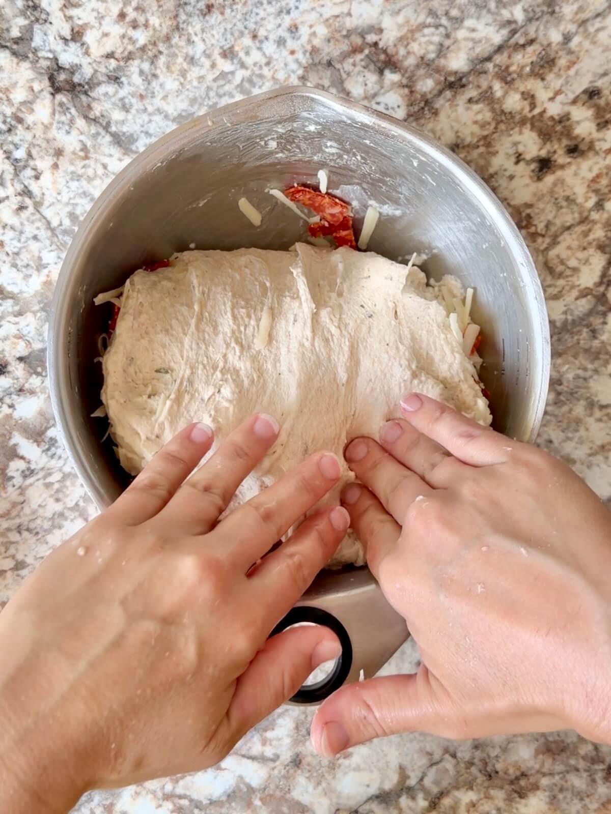Pepperoni, mozzarella, and parmesan cheese being folded into the dough.