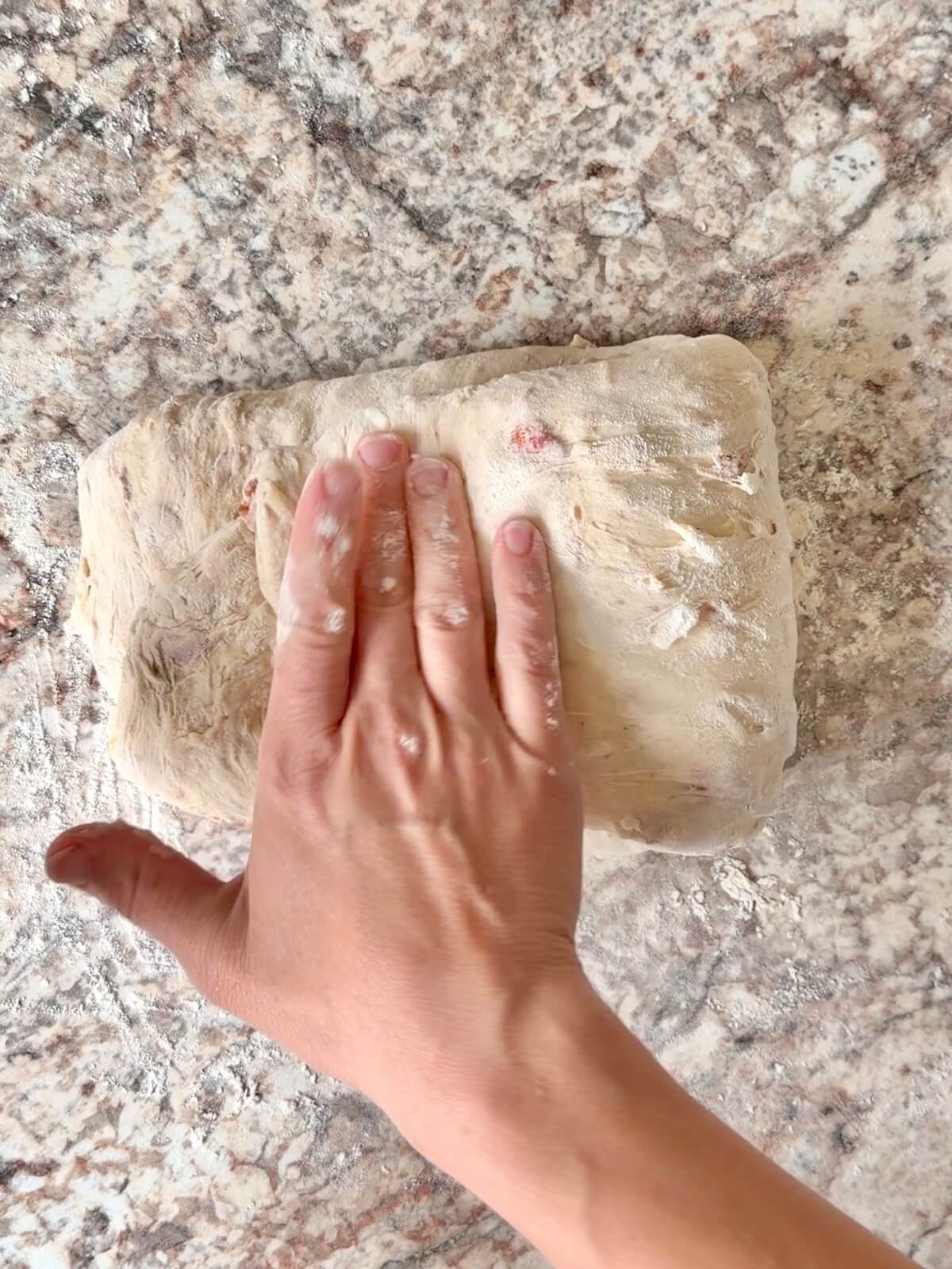 Sourdough pizza bread dough being shaped on a floured counter.