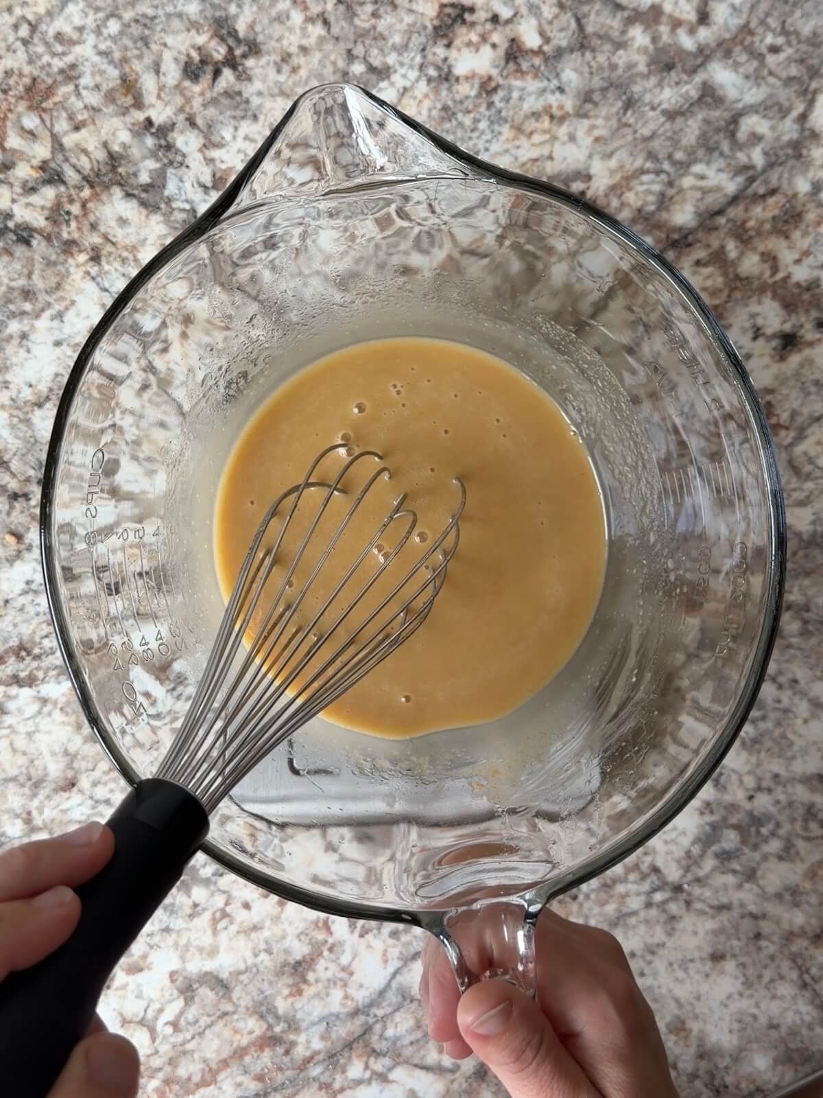 Sourdough discard, apple cider, and other wet ingredients whisked together in a bowl.