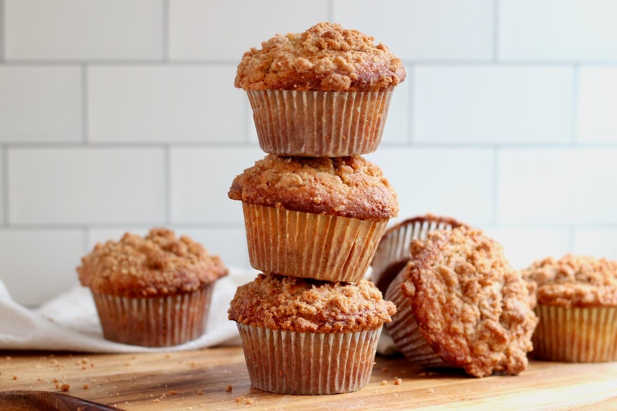 A stack of three sourdough discard apple muffins with a few more muffins out of focus in the background.