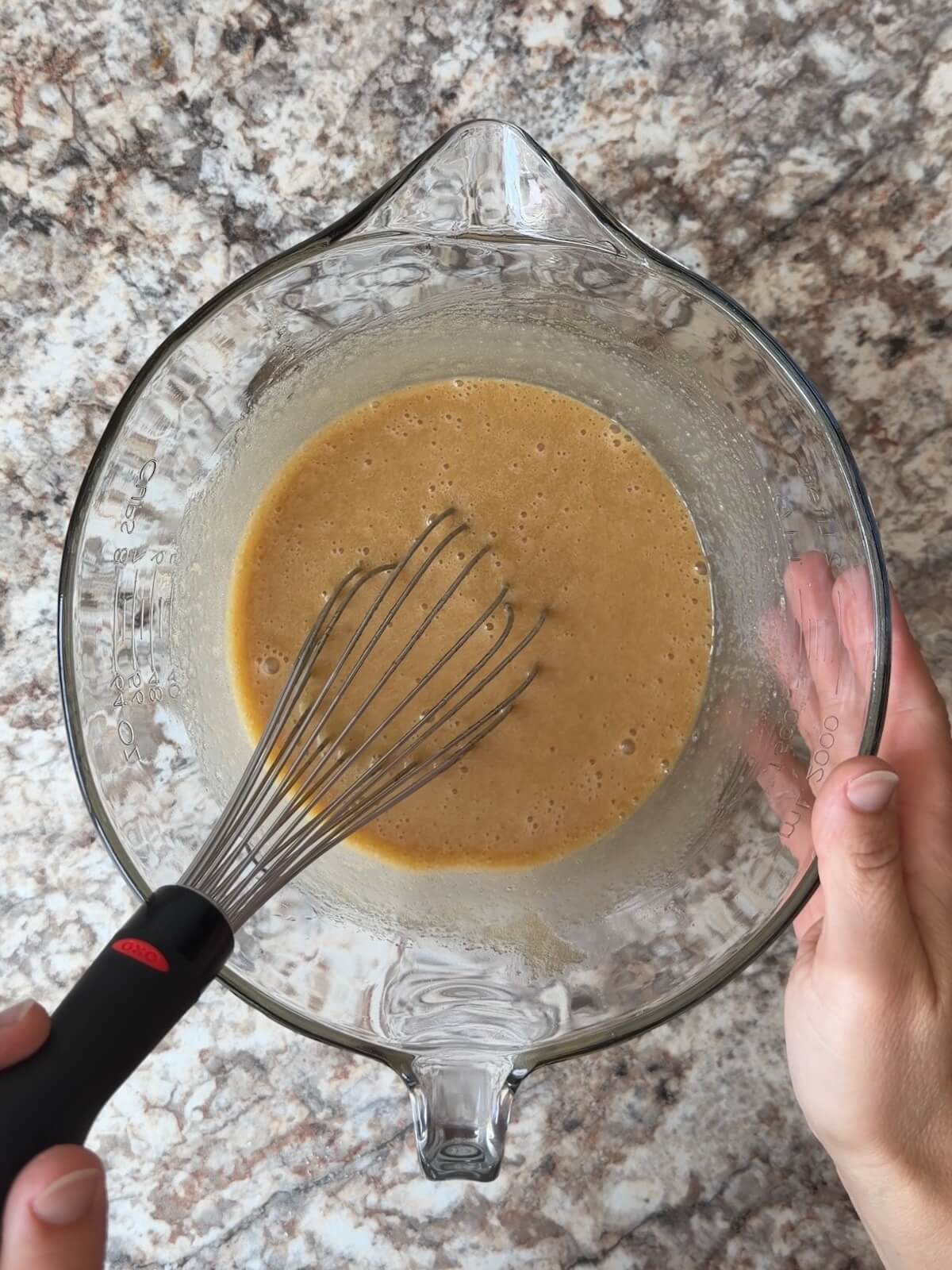 The wet ingredients, including sourdough discard, whisked together in a glass bowl.