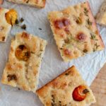 Pieces of sourdough discard focaccia on a wooden cutting board.