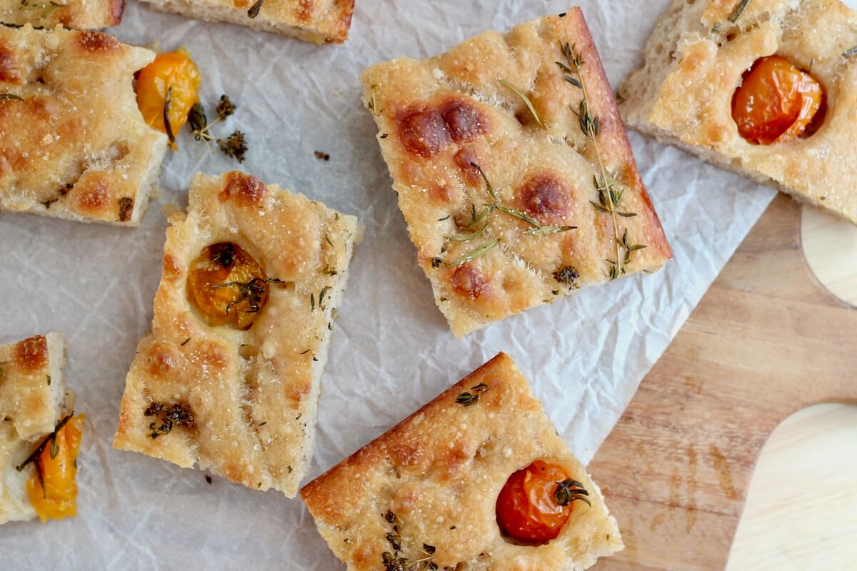 Pieces of sourdough discard focaccia on a wooden cutting board.