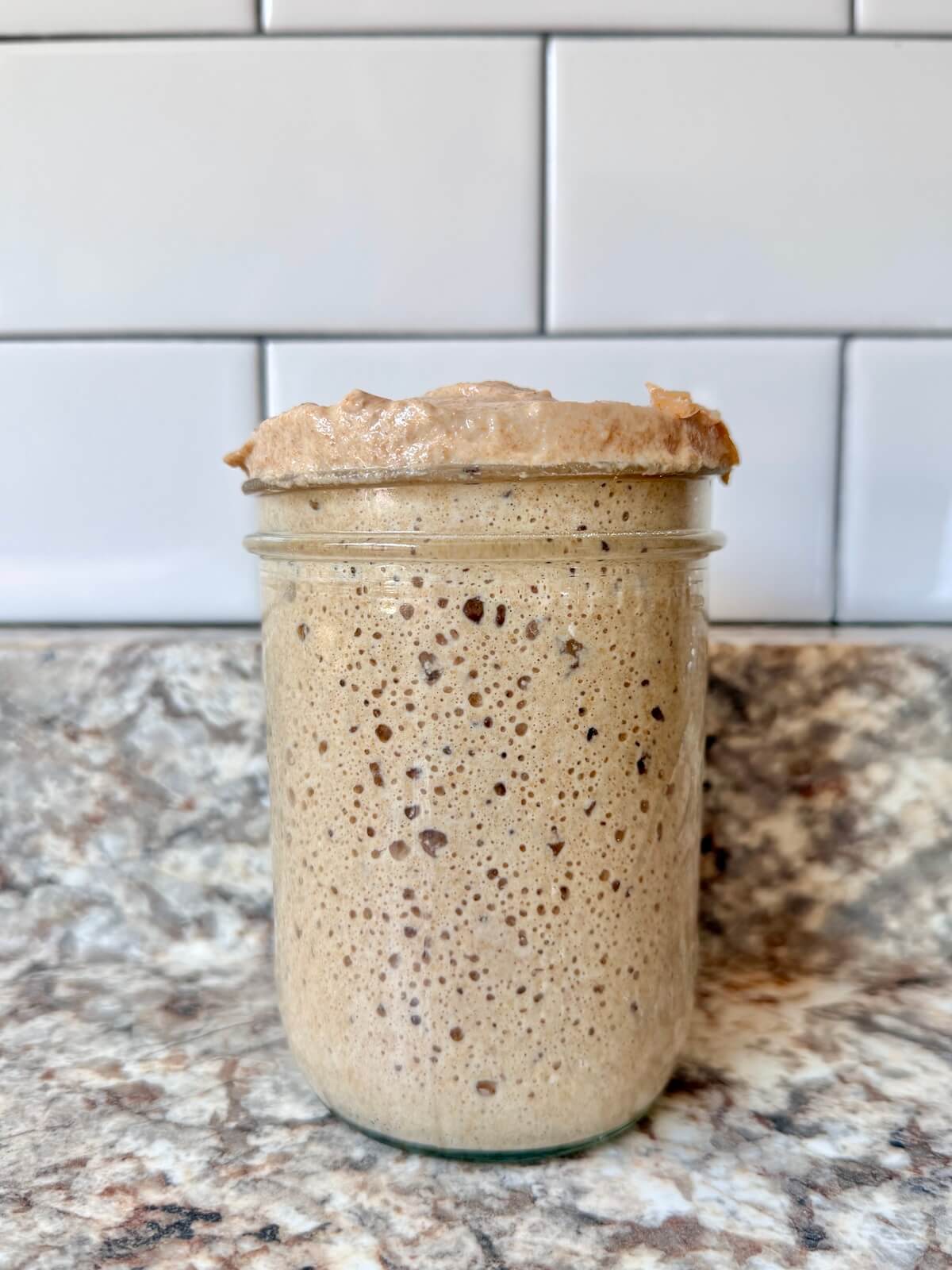An overflowing jar of sourdough starter.