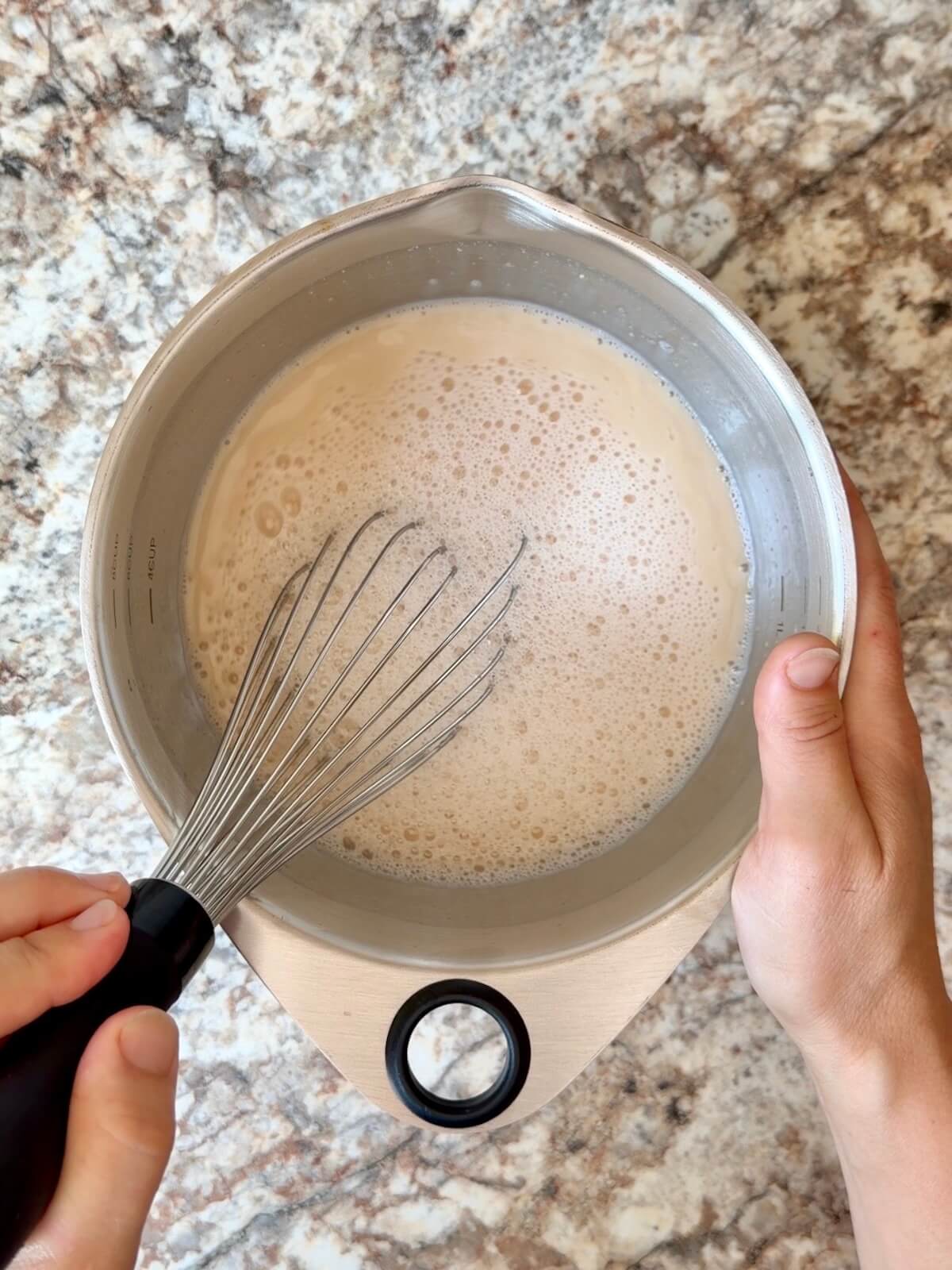 Sourdough starter and water whisked together in a mixing bowl.
