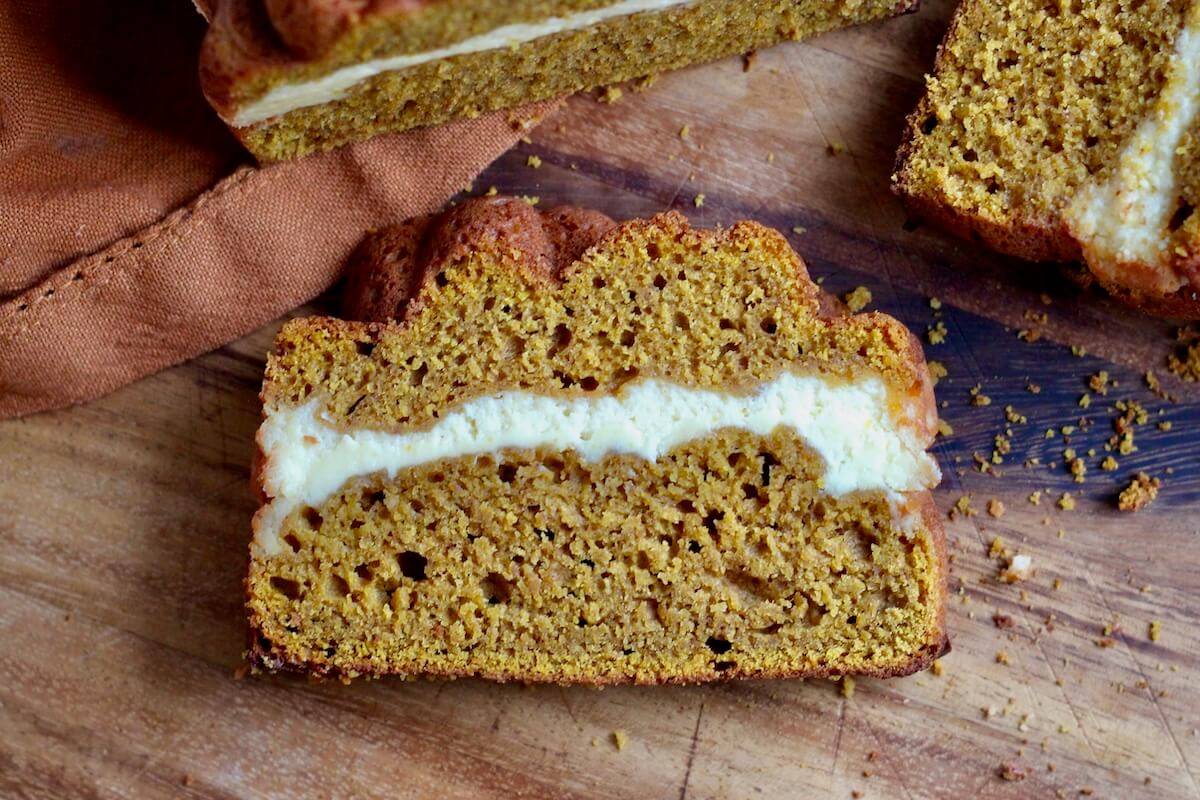 A slice of sourdough pumpkin cream cheese bread on a wooden cutting board.