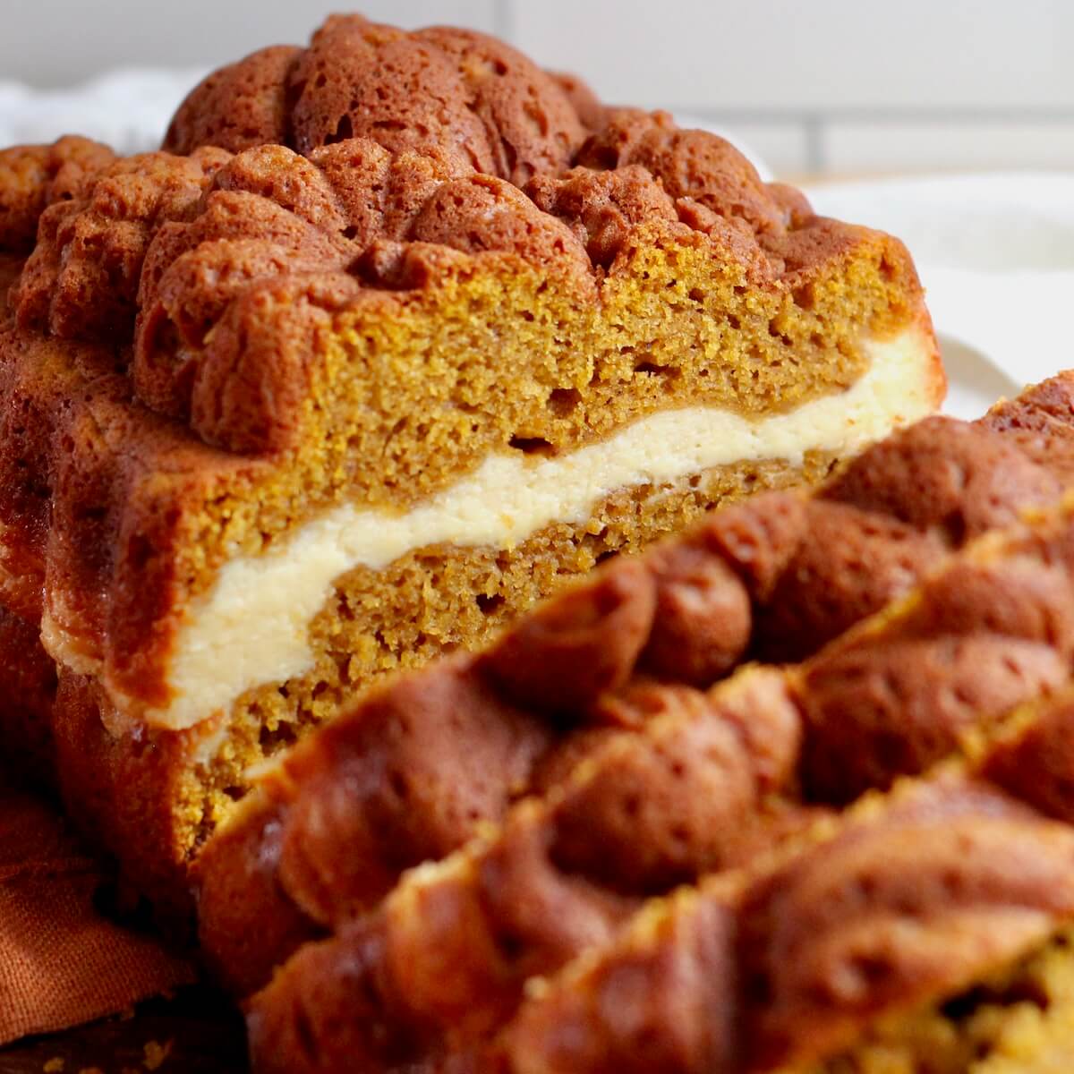A loaf of sourdough pumpkin cream cheese bread. Half of the loaf is cut into slices.