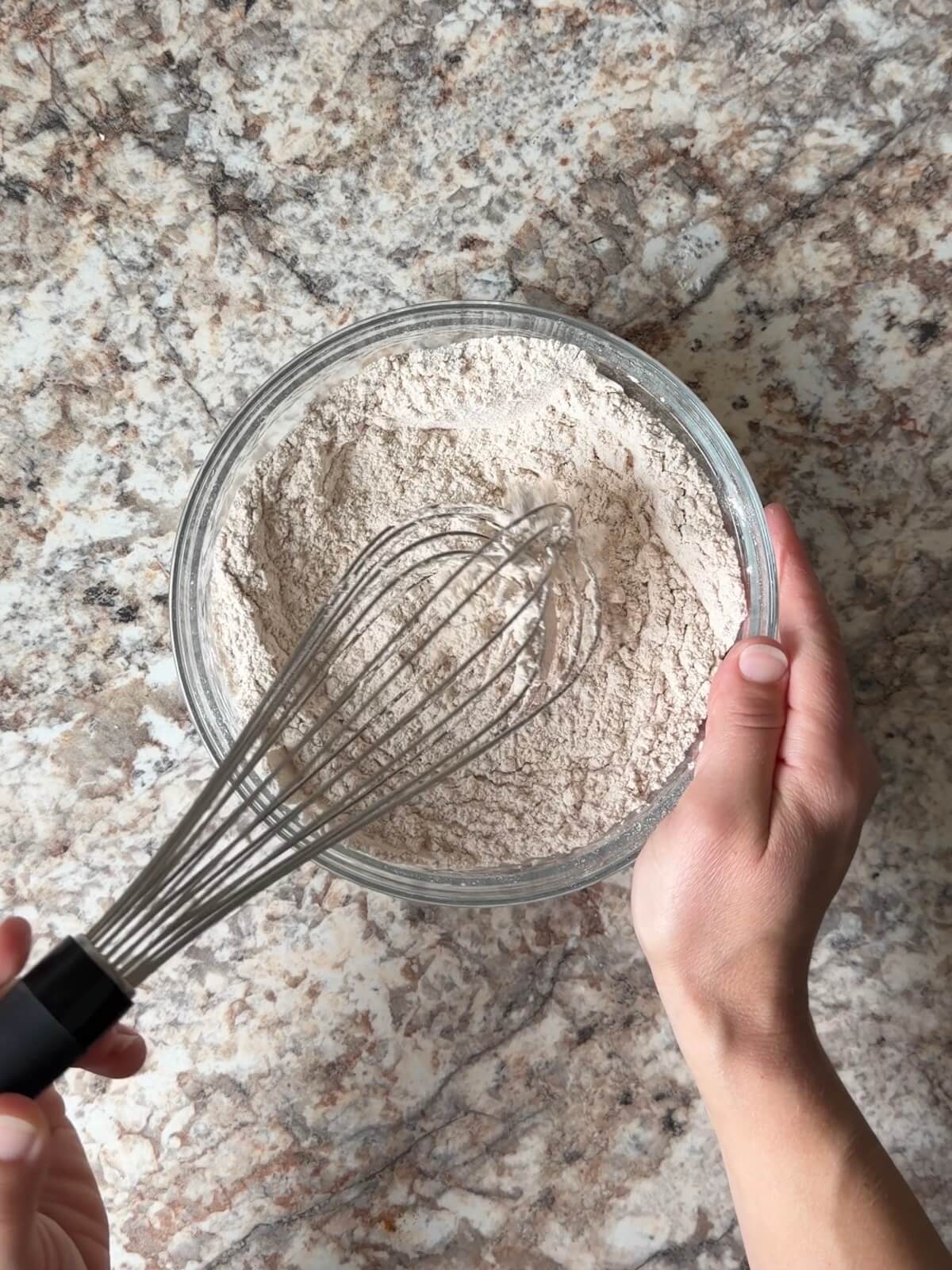 Flour, pumpkin spices, and other dry ingredients whisked together in a bowl.