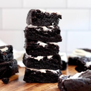 A stack of five black cocoa sourdough brownies with cream cheese frosting.