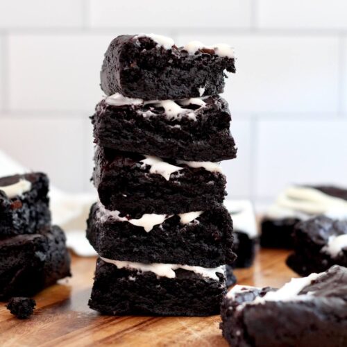 A stack of five black cocoa sourdough brownies with cream cheese frosting.
