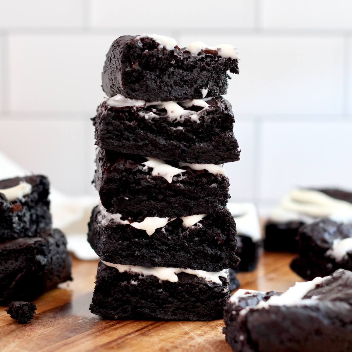 A stack of five black cocoa sourdough brownies with cream cheese frosting.