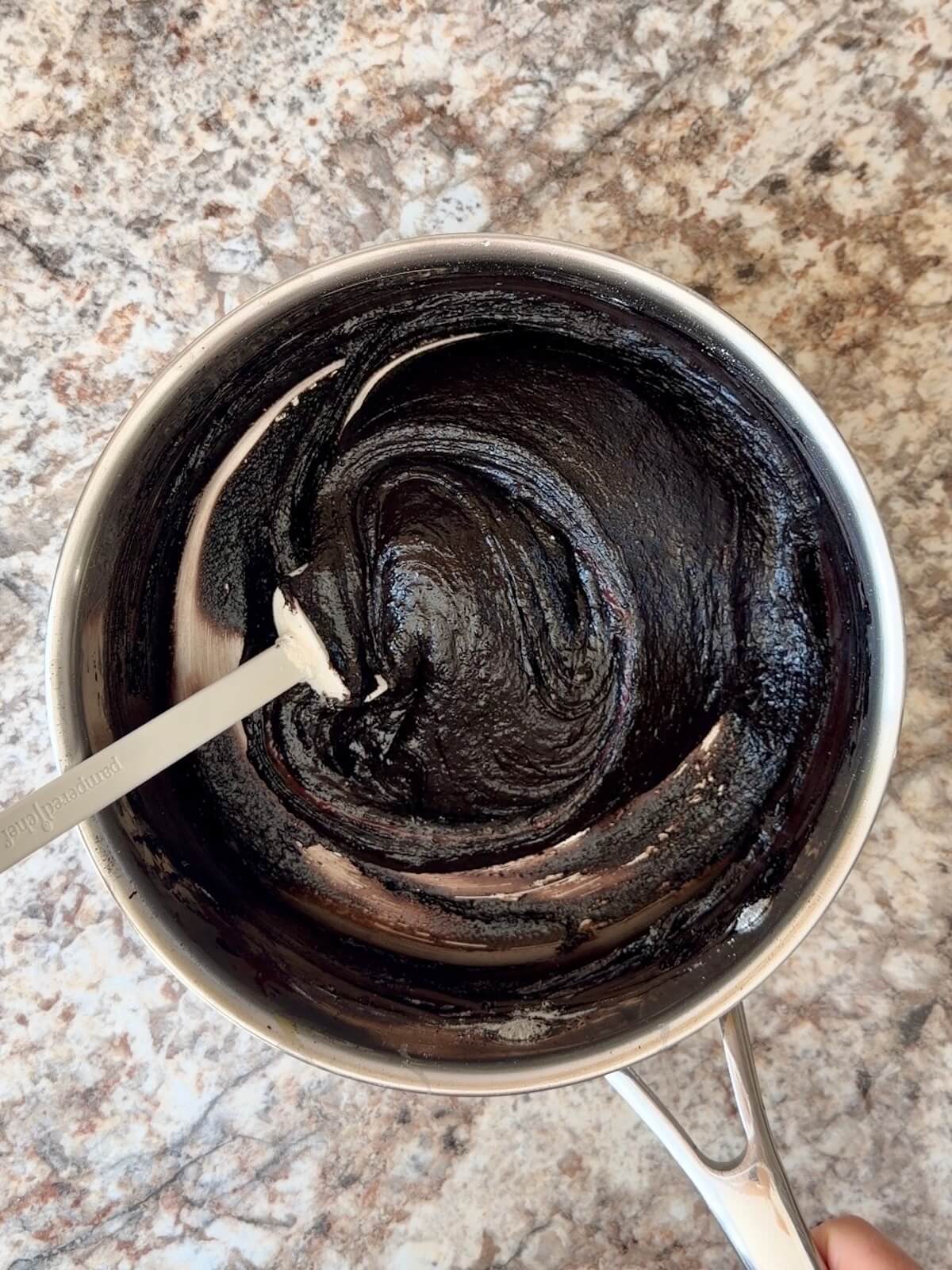 Black cocoa sourdough brownie batter in a stainless steel pot.