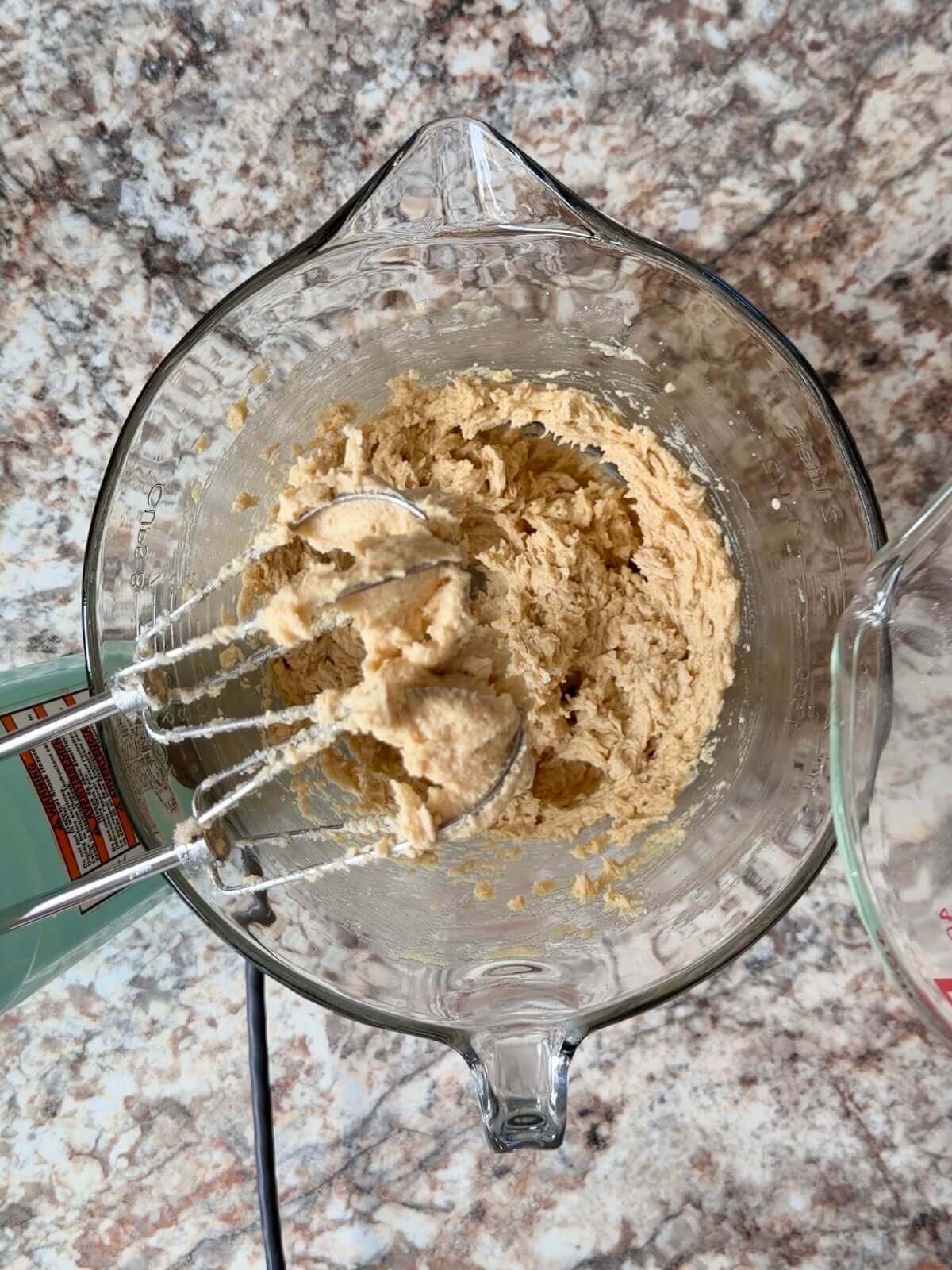 The wet ingredients beat together with a hand mixer in a large glass bowl.
