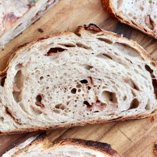 A slice of cinnamon apple sourdough bread on a wooden cutting board.