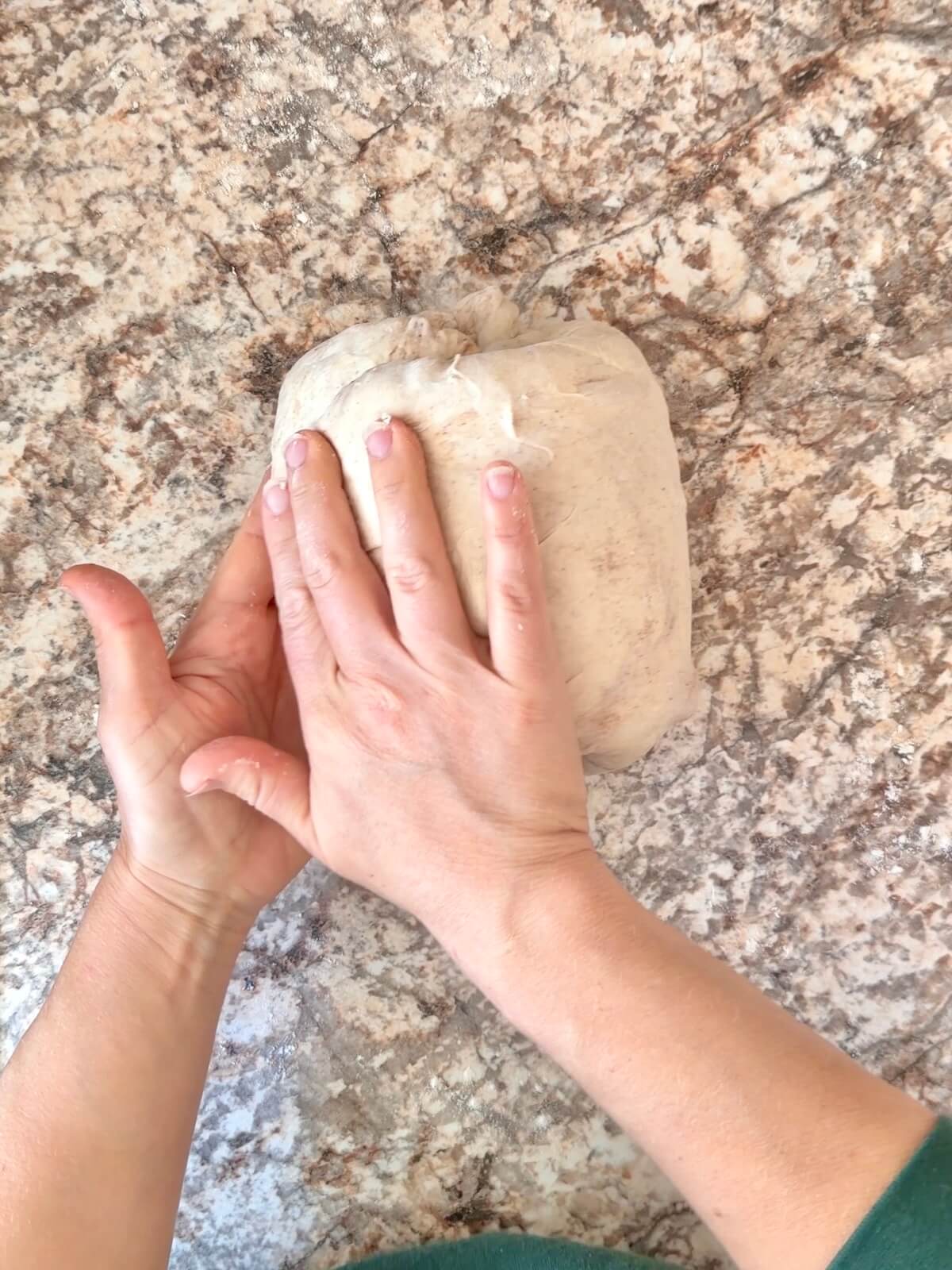 Cinnamon apple sourdough bread dough being shaped on a floured counter.
