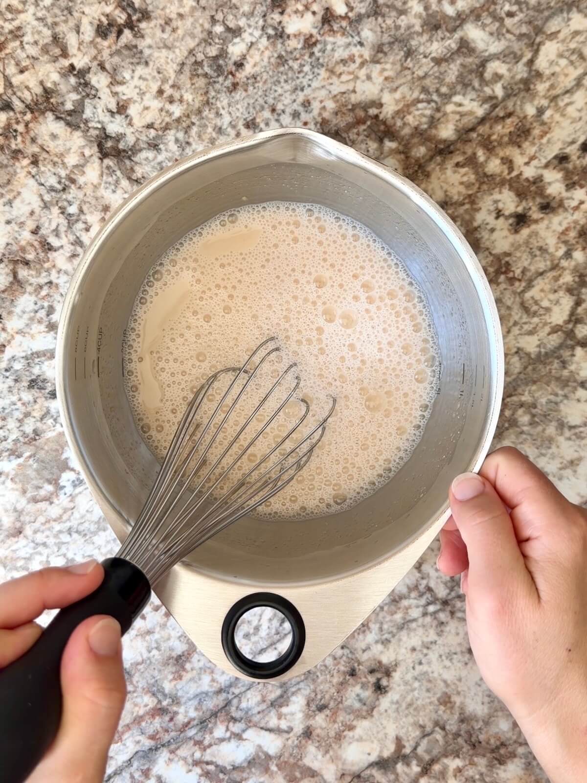 Active sourdough starter and water whisked together in a bowl.