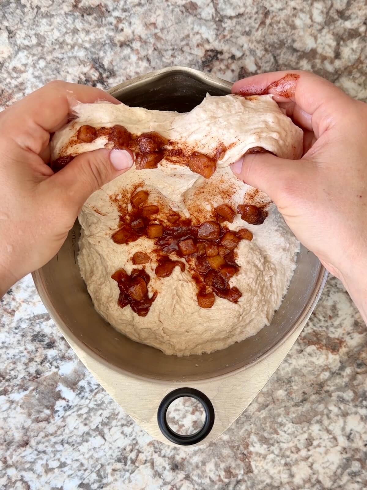 Sautéed cinnamon apples being stretched and folded into sourdough bread dough.