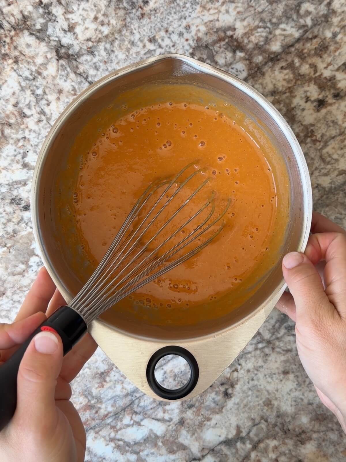 Sourdough starter, pumpkin puree, and water whisked together in a bowl.