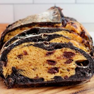 A loaf of Halloween sourdough bread sliced on a wooden cutting board.
