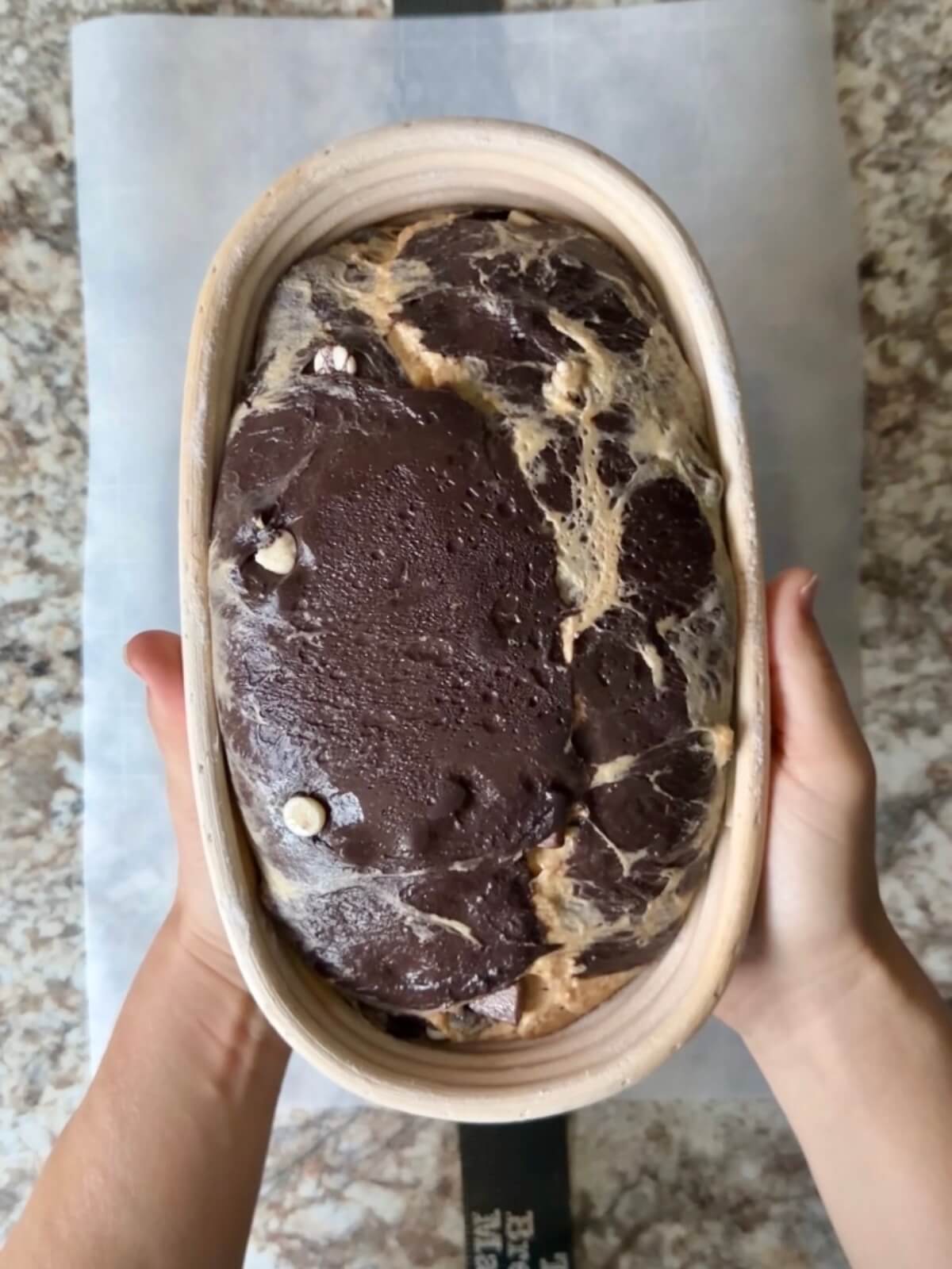 Black cocoa and pumpkin sourdough bread dough in an oval proofing basket after cold proofing overnight.