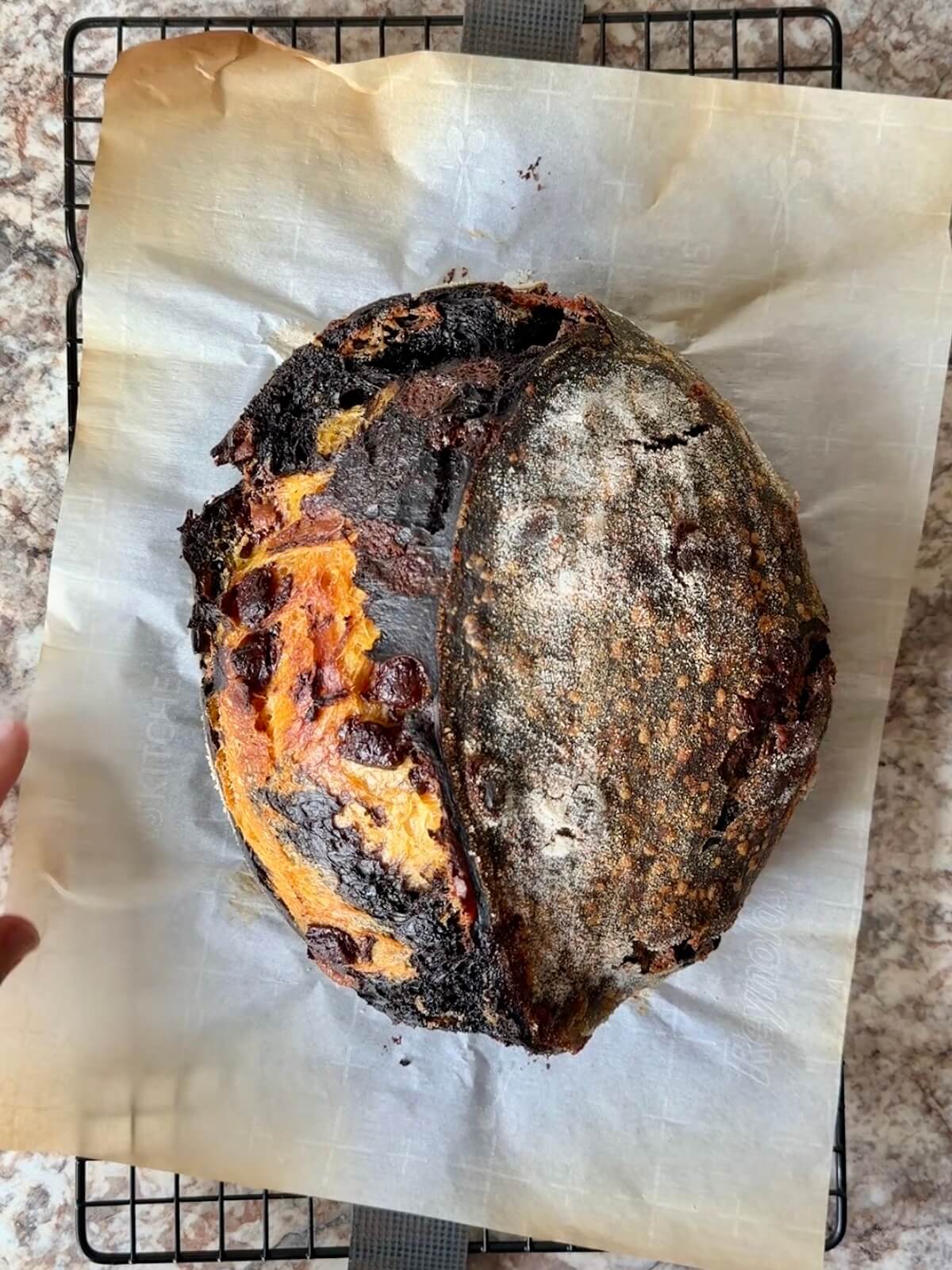 A baked loaf of Halloween sourdough bread on a wire cooling rack.
