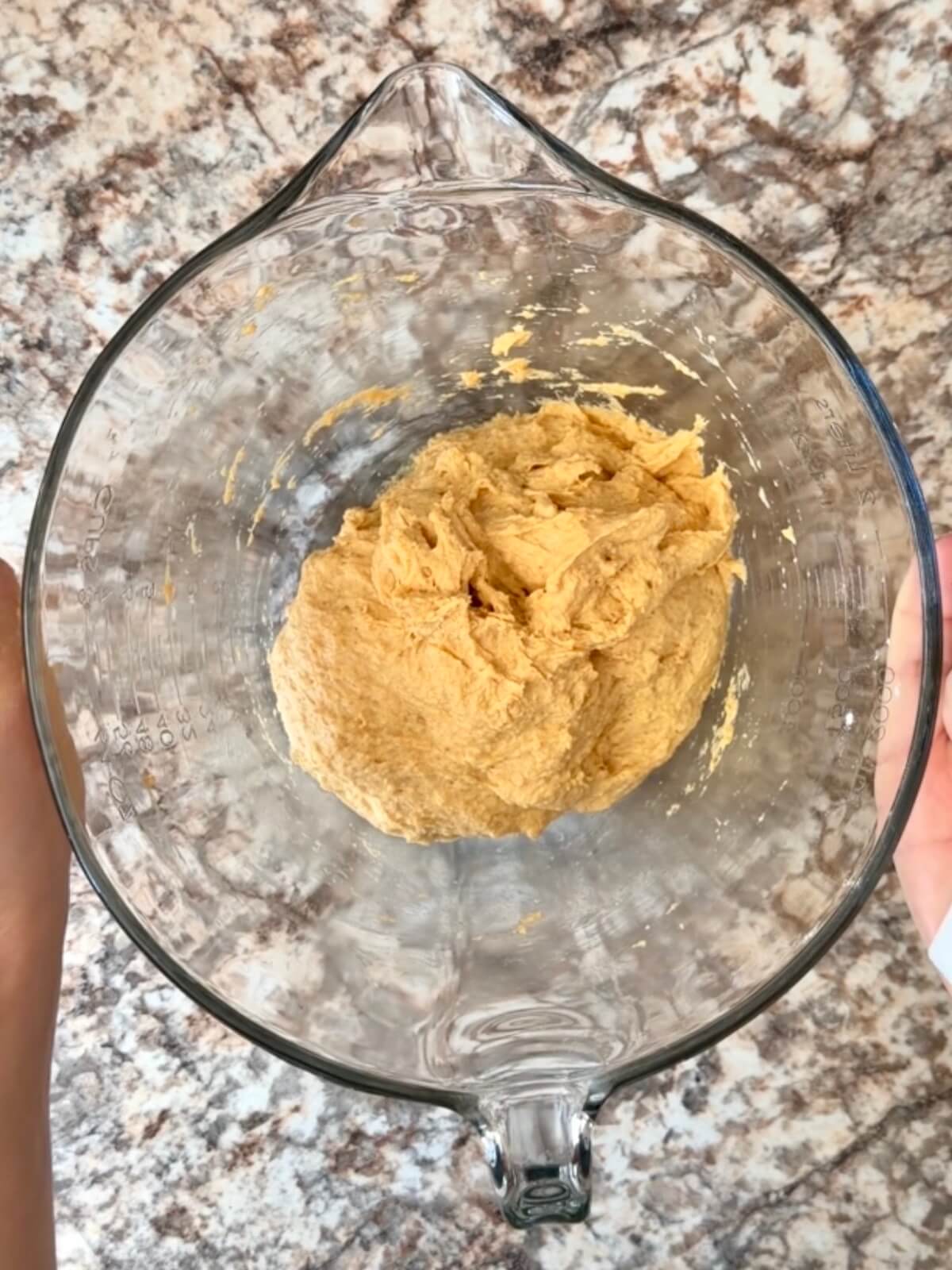 Pumpkin sourdough bread dough in a glass mixing bowl.