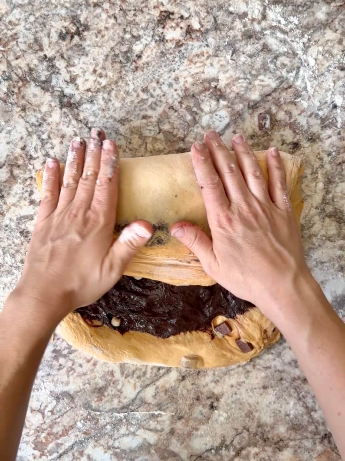 Halloween sourdough bread dough being shaped on a floured counter.