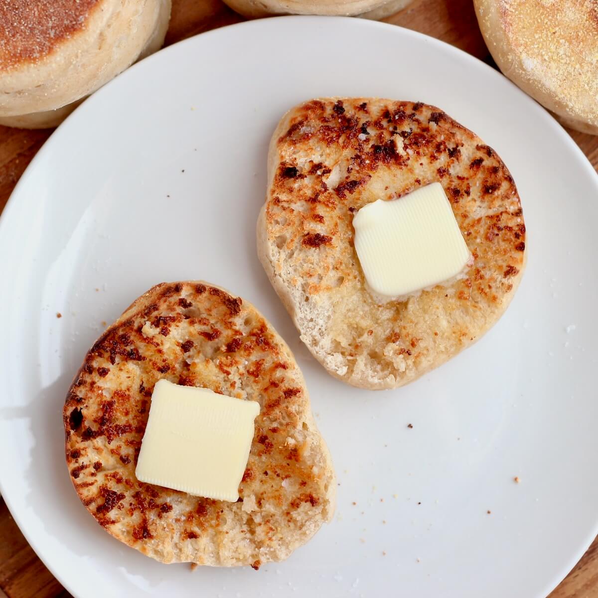 A toasted high-protein sourdough English muffin with butter on a small white plate.