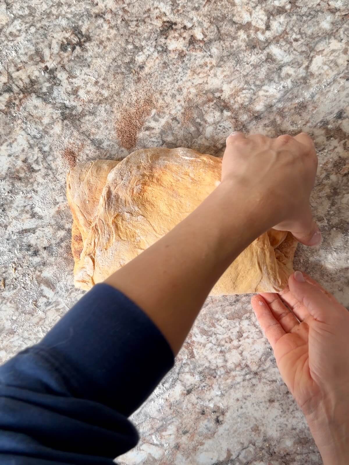 Pumpkin spice sourdough bread dough being shaped on a floured counter.