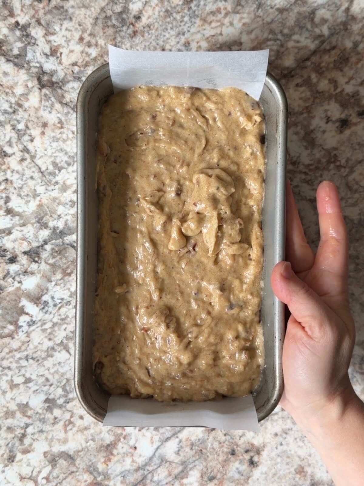 Sourdough discard banana bread batter in a parchment-lined loaf pan.