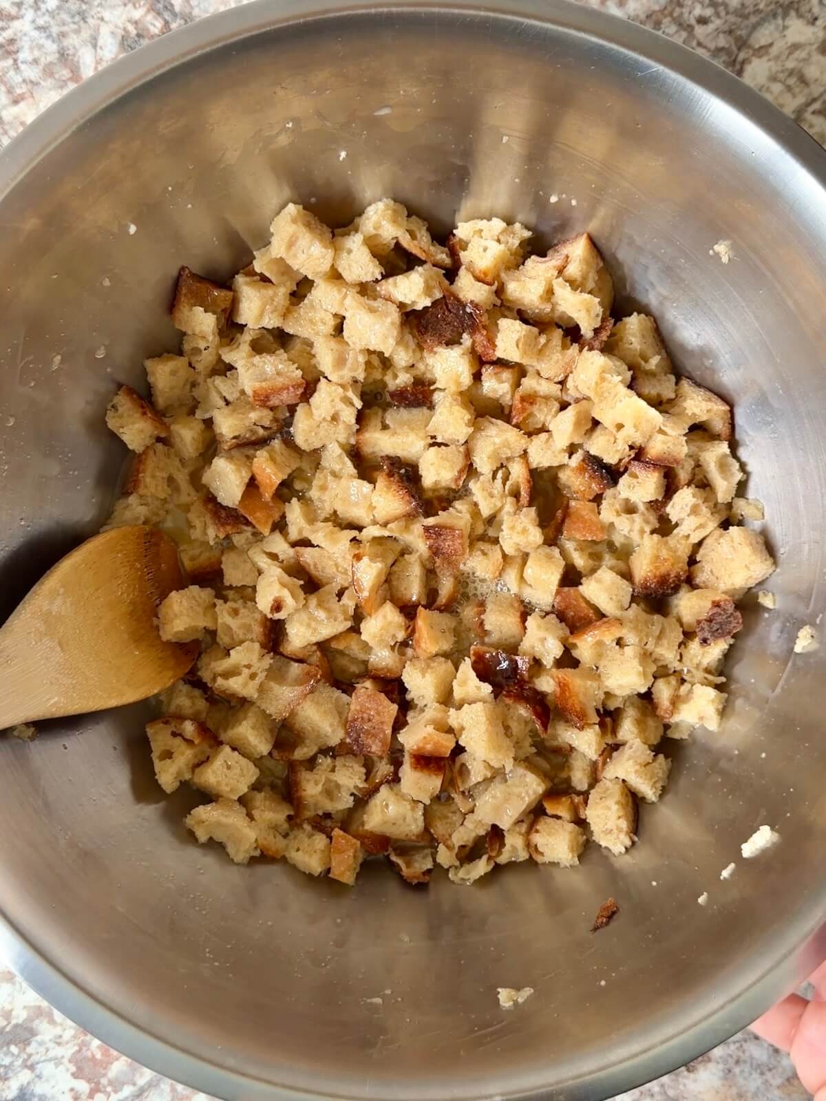 Sourdough bread cubes mixed with chicken stock and eggs in a large bowl.