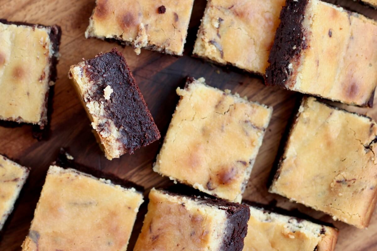 Sourdough cheesecake brownies cut into squares on a wooden cutting board.