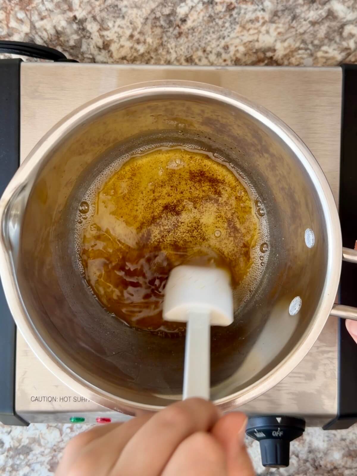Butter being browned in a stainless steel saucepan.